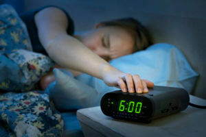 woman shutting off alarm clock